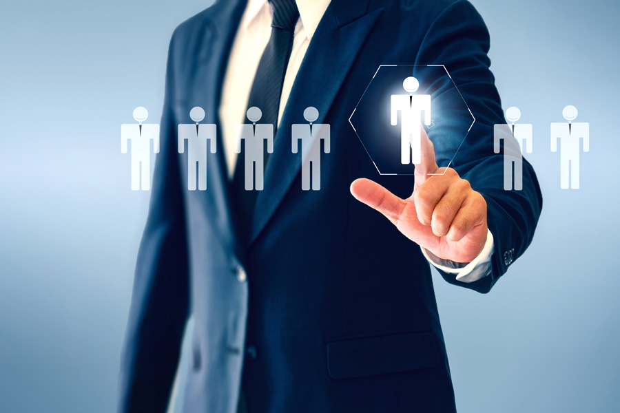 Businessman in a suit selecting a person icon from a lineup of icons, representing the recruitment and selection process.